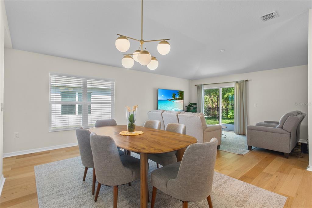 A dining area with a wooden table and chairs sits in front of a living room — 4621 GLENCREST LOOP, ST CLOUD, FL