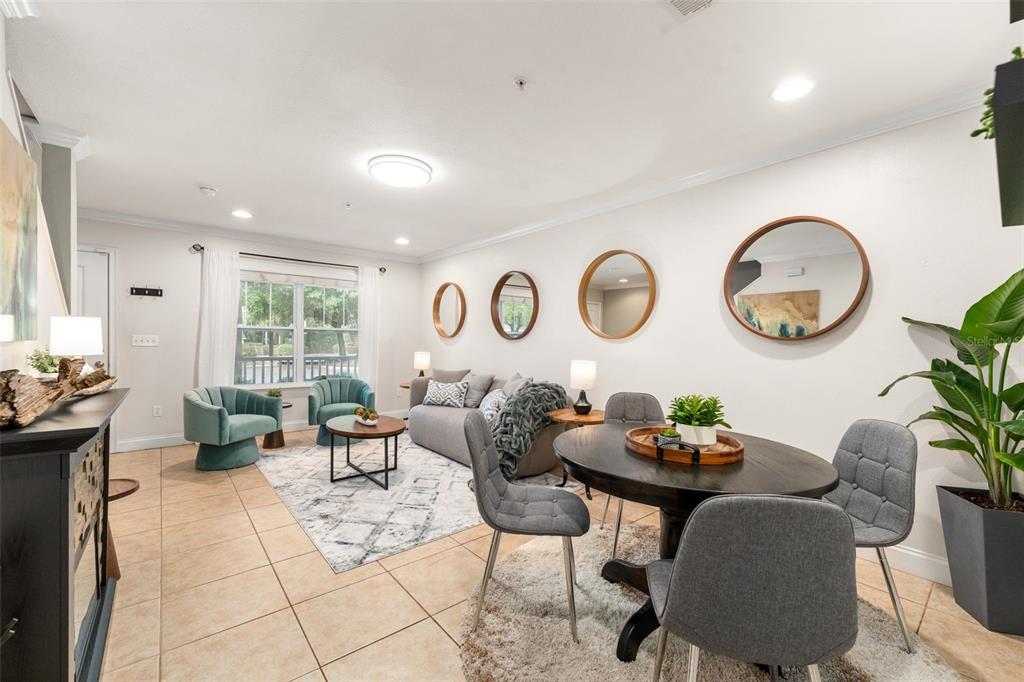 A living room with tile floors, a fireplace, teal armchairs, and a dining area — 4639 SW 48TH DRIVE UNIT 151, GAINESVILLE, FL