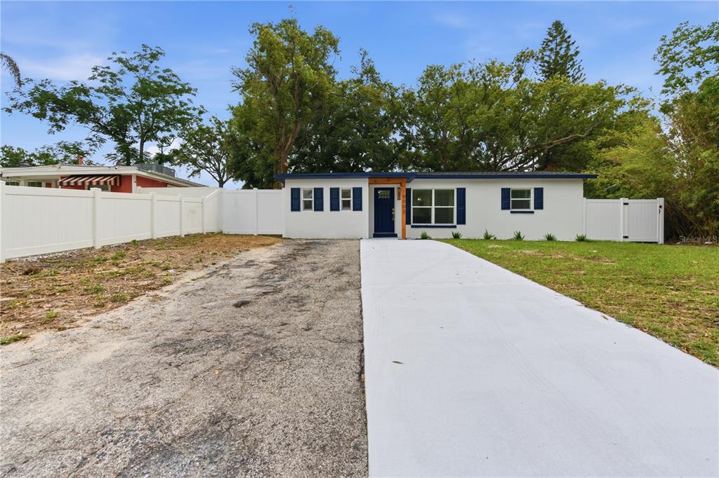 A single-story white house features a blue front door, blue shutters, and a concrete driveway — 10003 N 24TH STREET, TAMPA, FL