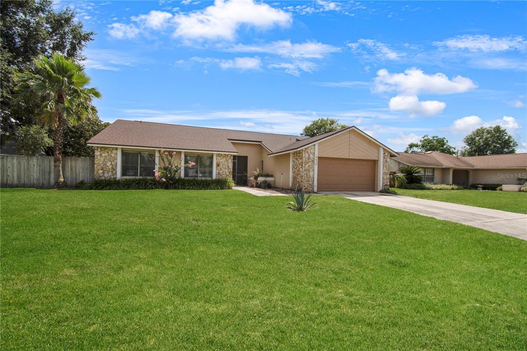 A single-story house with a stone facade, brown roof, and attached garage sits on a lawn — 8628 GRANADA BOULEVARD, ORLANDO, FL