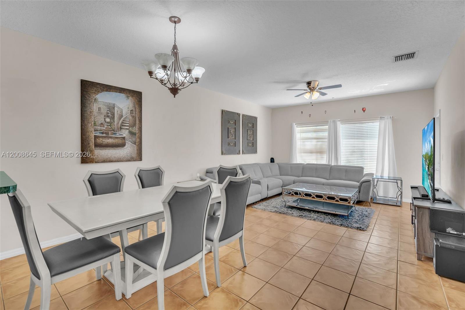 A dining area and living room with tile floors, a sectional sofa, and a chandelier — 4266 SW 10th Pl, Deerfield Beach FL 33442, DEERFIELD BEACH, FL