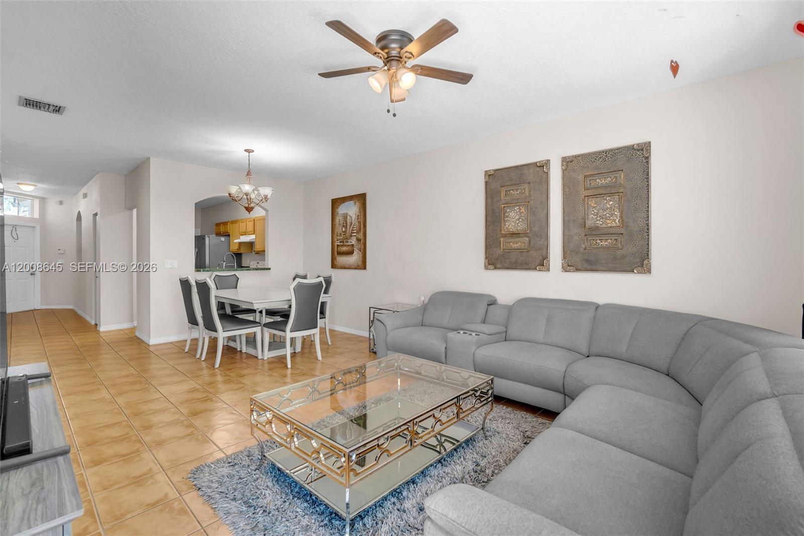 A living room with a gray sectional sofa, glass coffee table, and adjacent dining area — 4266 SW 10th Pl, Deerfield Beach FL 33442, DEERFIELD BEACH, FL