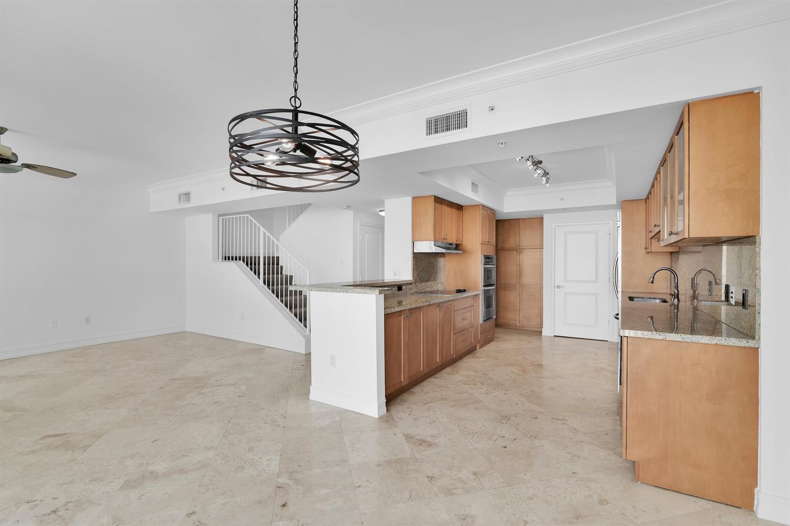 A kitchen with light wood cabinets and granite countertops opens to a living area — 99 SE Mizner Boulevard # 40, Boca Raton FL 33432, BOCA RATON, FL