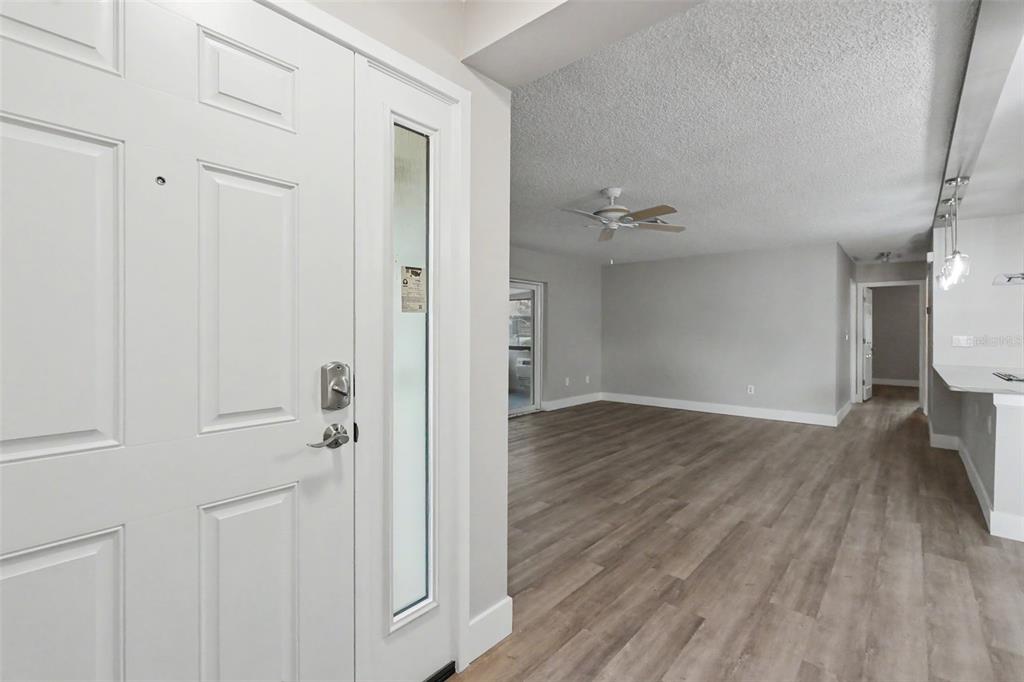 A white front door opens into a living area with light gray walls and wood flooring — 1502 16TH CIRCLE SE, LARGO, FL