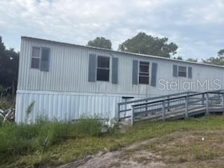 A light-colored mobile home with a wooden wheelchair ramp leading to the entrance — 150 CARLTON MILLENDER ROAD, CARRABELLE, FL