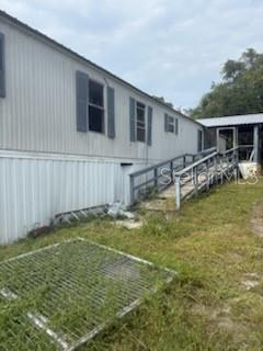 The exterior of a mobile home features light-colored siding, dark shutters, and a wooden ramp — 150 CARLTON MILLENDER ROAD, CARRABELLE, FL