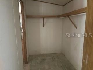 A walk-in closet with white walls, a wooden shelf, and a bare concrete floor — 150 CARLTON MILLENDER ROAD, CARRABELLE, FL