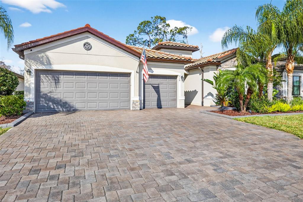 A single-story house with a paved driveway, two garage doors, and a tiled roof — 710 ACACIA COURT, BRADENTON, FL