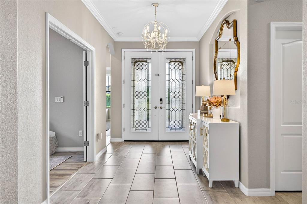 A bright entryway features a white double door, tile flooring, and a decorative console table — 710 ACACIA COURT, BRADENTON, FL