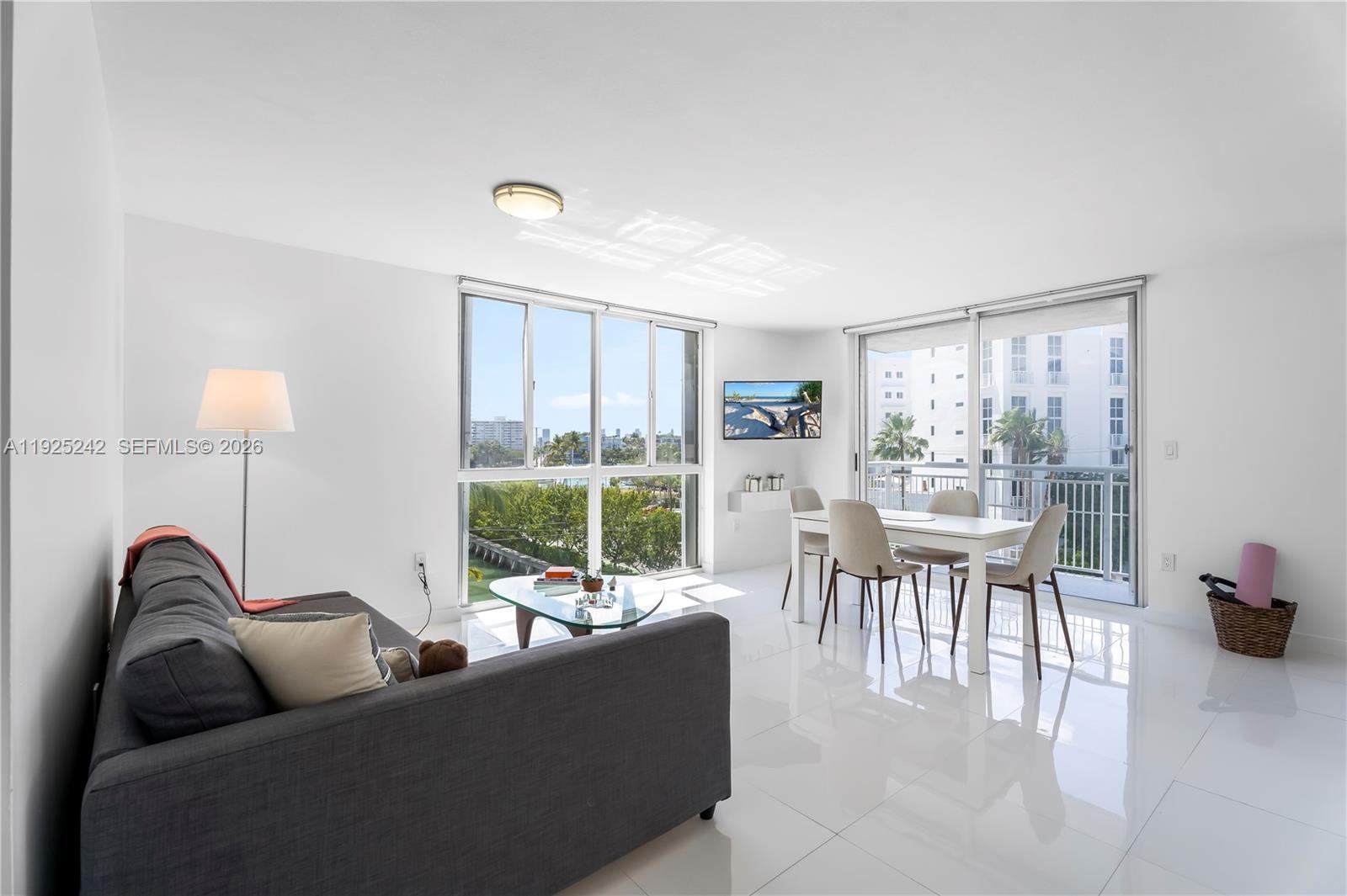 A bright living and dining area features white tile floors, large windows, and a balcony — 1688 West Ave # 401, Miami Beach FL 33139, MIAMI BEACH, FL