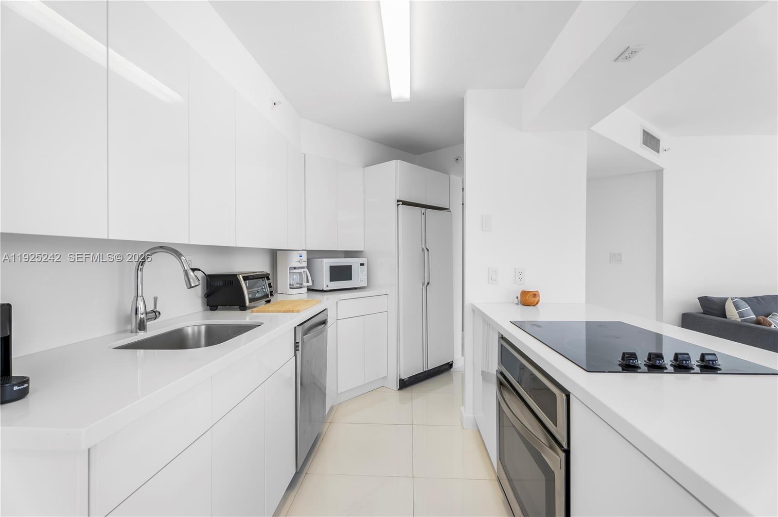 A modern kitchen features white cabinetry, stainless steel appliances, and a white countertop — 1688 West Ave # 401, Miami Beach FL 33139, MIAMI BEACH, FL