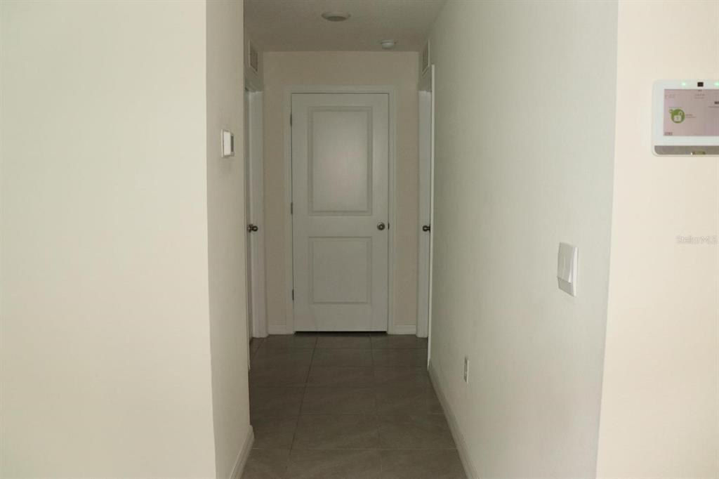 A hallway with light-colored walls, tile flooring, and three white interior doors — 1668 HAZY SEA DRIVE, PLANT CITY, FL
