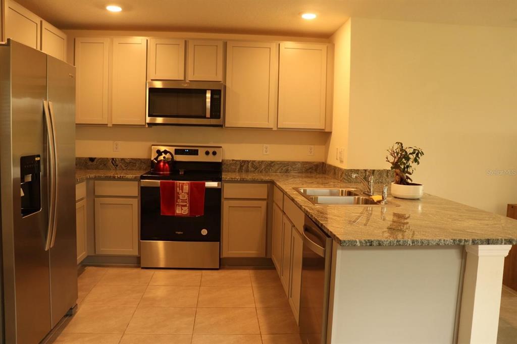 A kitchen with stainless steel appliances, light-colored cabinets, and granite countertops — 1668 HAZY SEA DRIVE, PLANT CITY, FL