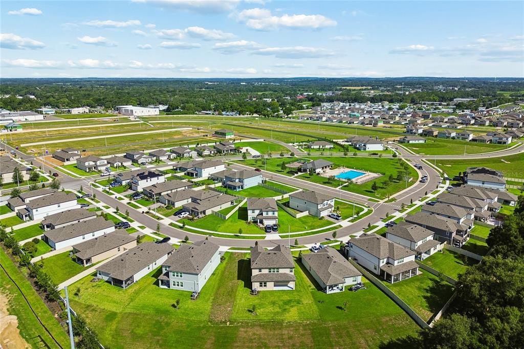An aerial view shows a suburban neighborhood with single-family homes, green lawns, and a pool — 12177 FARRIER DRIVE, DADE CITY, FL