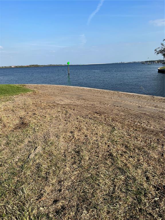 A grassy lot slopes down toward a body of water with a green navigation marker — 12437 RAN TERRACE, PORT CHARLOTTE, FL