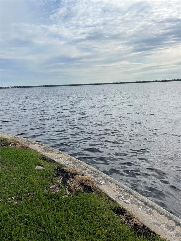 A concrete seawall borders a grassy lawn overlooking a large body of water — 12437 RAN TERRACE, PORT CHARLOTTE, FL