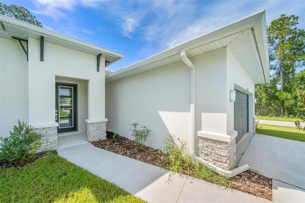 A white stucco house exterior features a front entrance, a garage, and stone accents — 17 EL DORADO BOULEVARD N, CAPE CORAL, FL