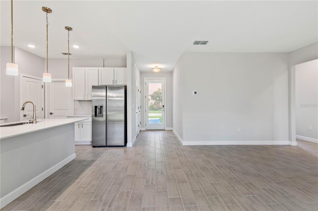 A kitchen with white cabinets and stainless steel appliances opens to a tiled living area — 17 EL DORADO BOULEVARD N, CAPE CORAL, FL