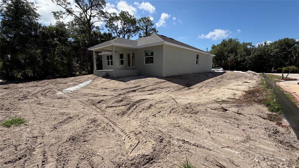 A newly constructed house with a covered patio sits on a cleared, sandy lot — 17492 QUINCY AVENUE, PORT CHARLOTTE, FL