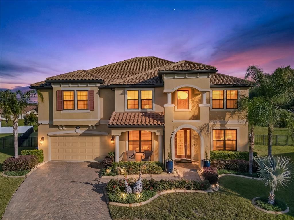 A two-story stucco house with a tile roof, arched entryway, and a paved driveway — 3905 AQUILLA DRIVE, LAKELAND, FL