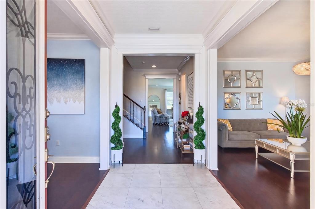 A bright foyer with tile flooring leads into a living room with dark wood floors — 3905 AQUILLA DRIVE, LAKELAND, FL