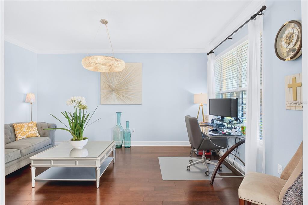 A living room with a gray sofa, glass coffee table, and a desk near a window — 3905 AQUILLA DRIVE, LAKELAND, FL