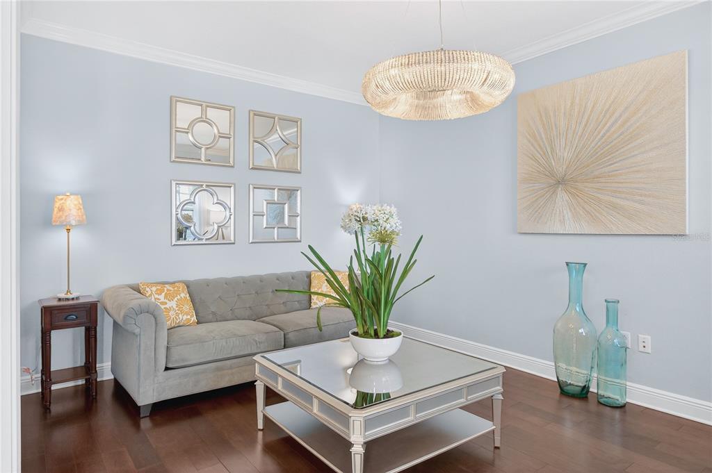 A living room features a gray tufted sofa, mirrored coffee table, and light blue walls — 3905 AQUILLA DRIVE, LAKELAND, FL