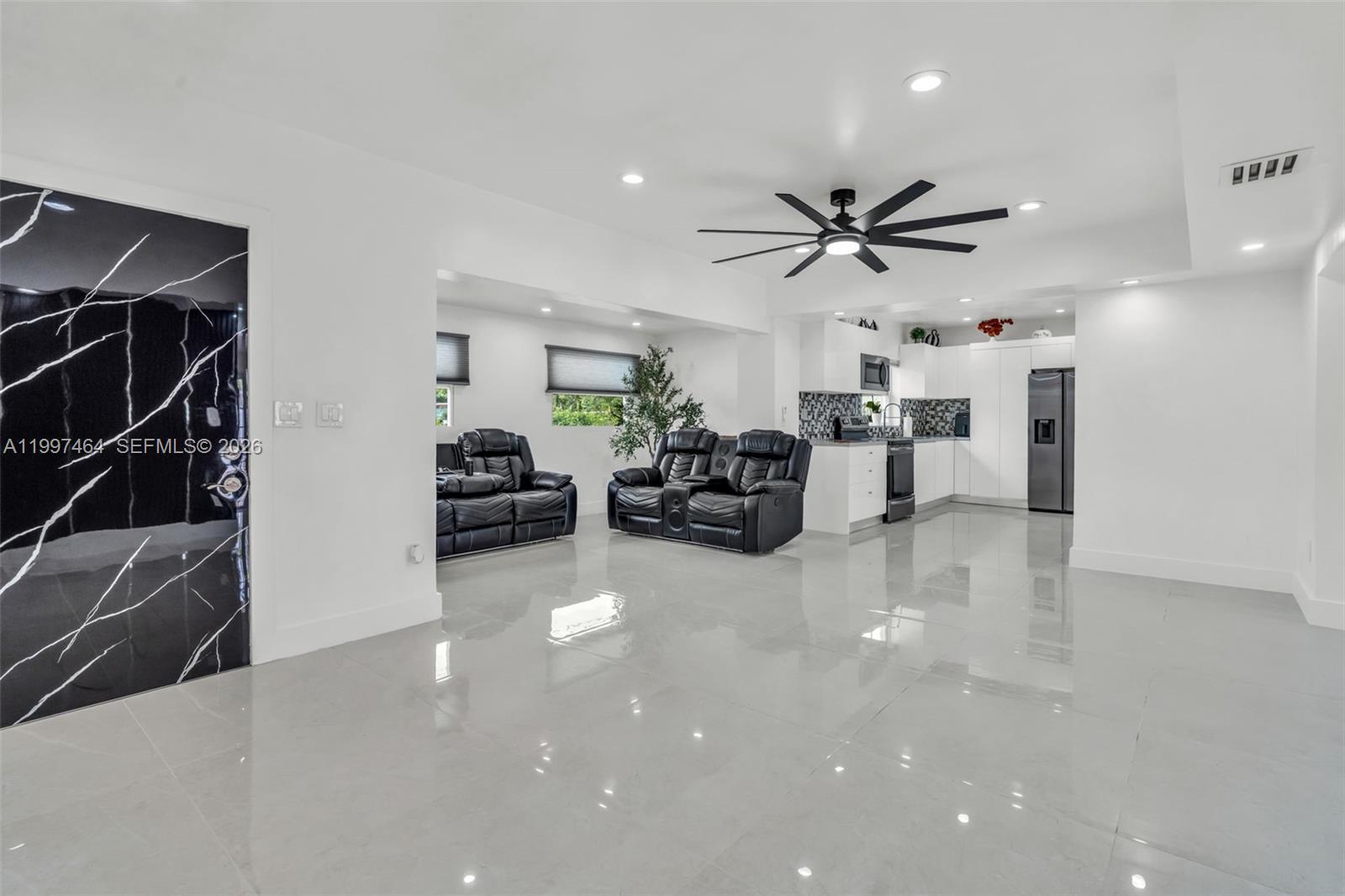 A modern open-concept living room and kitchen feature white walls, glossy tile floors, and furniture — 1055 NE 144th St, North Miami FL 33161, NORTH MIAMI, FL