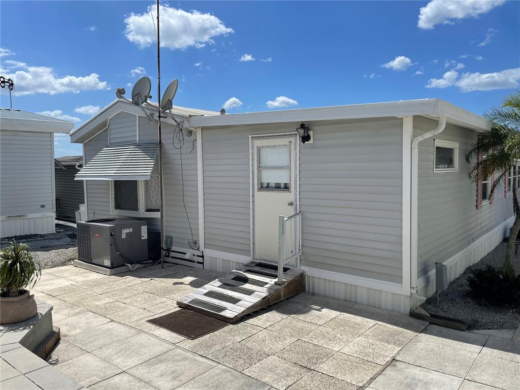 A light gray mobile home exterior features a ramp leading to a white entry door — 251 PATTERSON ROAD UNIT C-31, HAINES CITY, FL