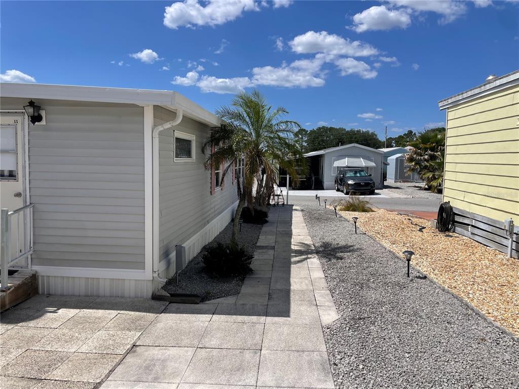 A paved walkway runs between two mobile homes with gravel landscaping and a palm tree — 251 PATTERSON ROAD UNIT C-31, HAINES CITY, FL