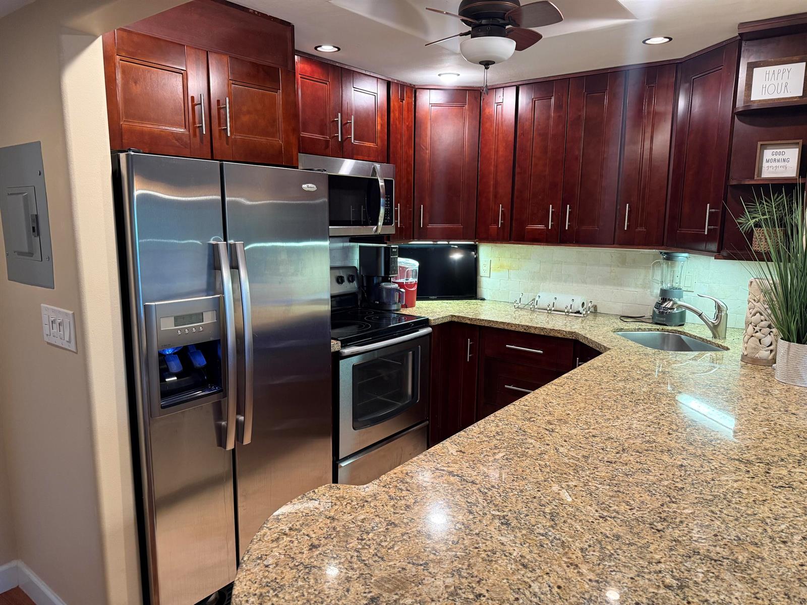 A kitchen features dark wood cabinets, granite countertops, and stainless steel appliances — 259 S Cypress Road # 545, Pompano Beach FL 33060, POMPANO BEACH, FL