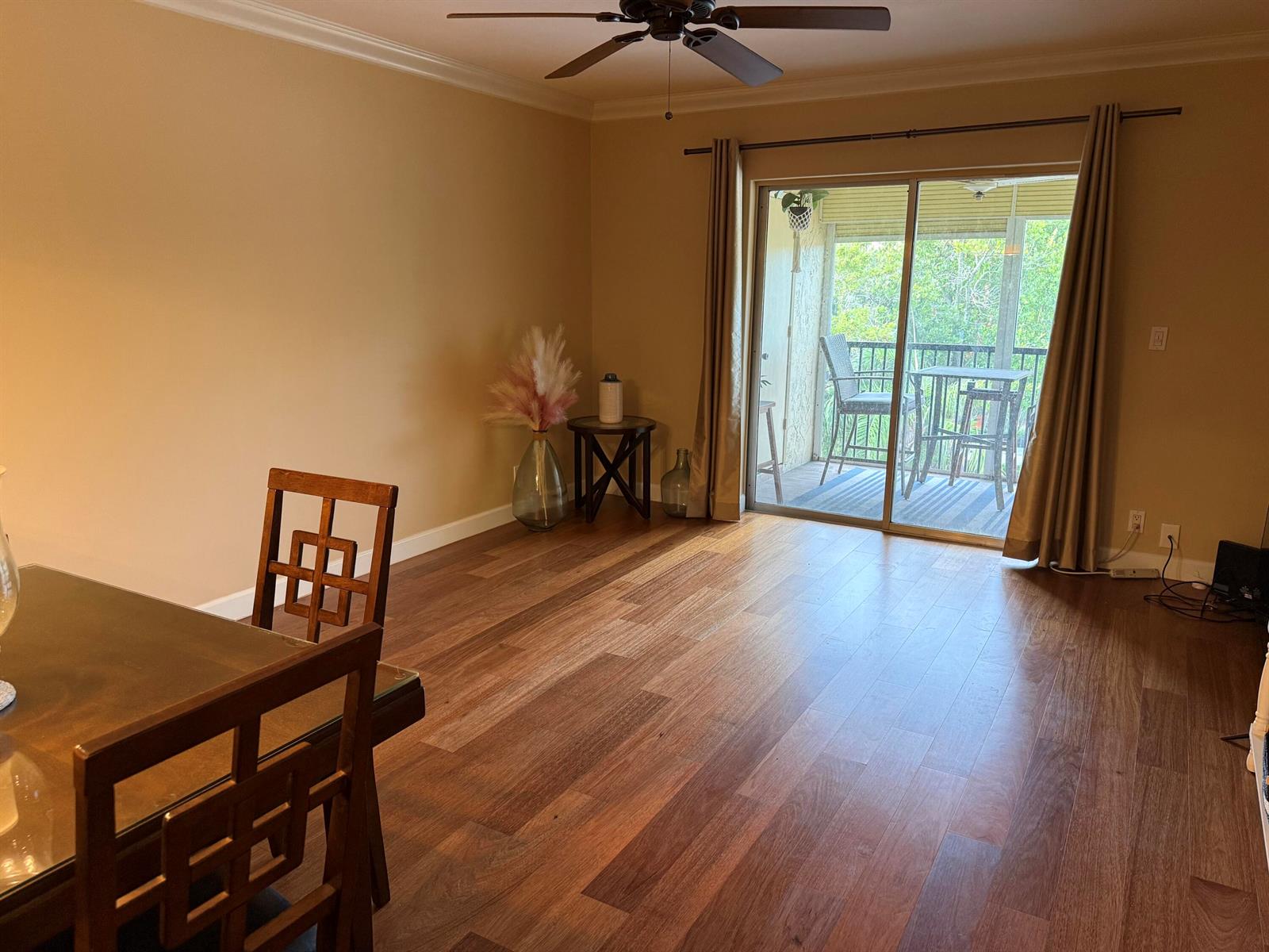 A dining area with wood flooring, a ceiling fan, and sliding doors leading to a balcony — 259 S Cypress Road # 545, Pompano Beach FL 33060, POMPANO BEACH, FL