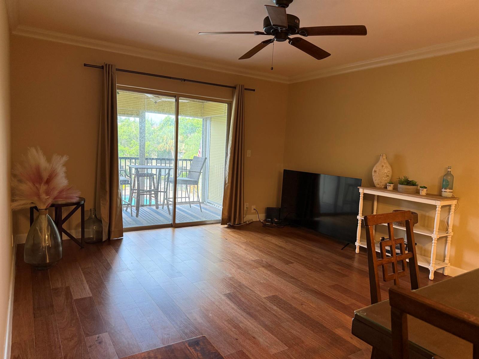 A living room with wood-look flooring, a ceiling fan, and a sliding glass door to a balcony — 259 S Cypress Road # 545, Pompano Beach FL 33060, POMPANO BEACH, FL