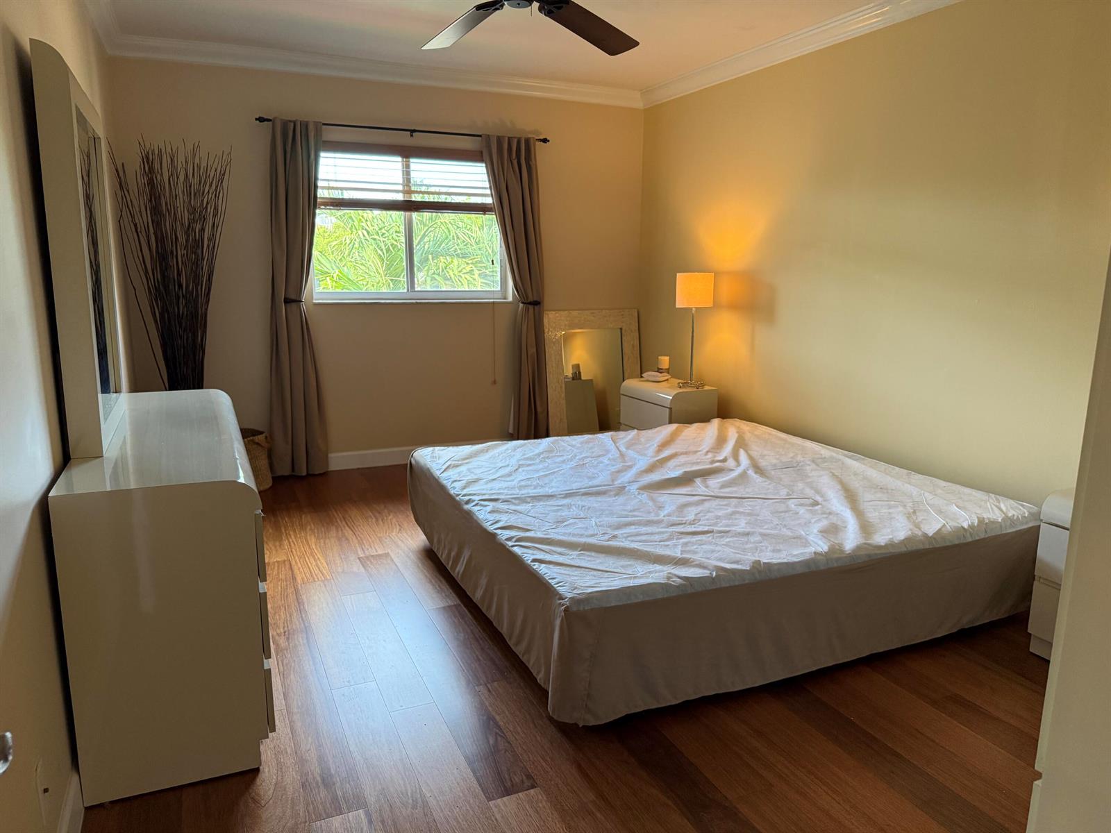 A bedroom features a bed, white dresser, floor mirror, and wood flooring under a ceiling fan — 259 S Cypress Road # 545, Pompano Beach FL 33060, POMPANO BEACH, FL