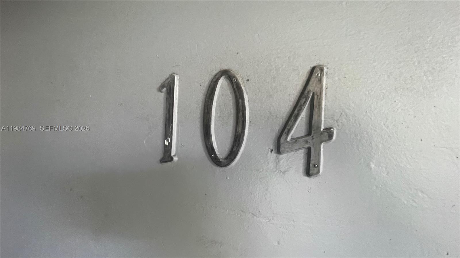 The number 104 is mounted on a plain, light-colored wall — 13700 NE 6th Ave # 104, North Miami FL 33161, NORTH MIAMI, FL