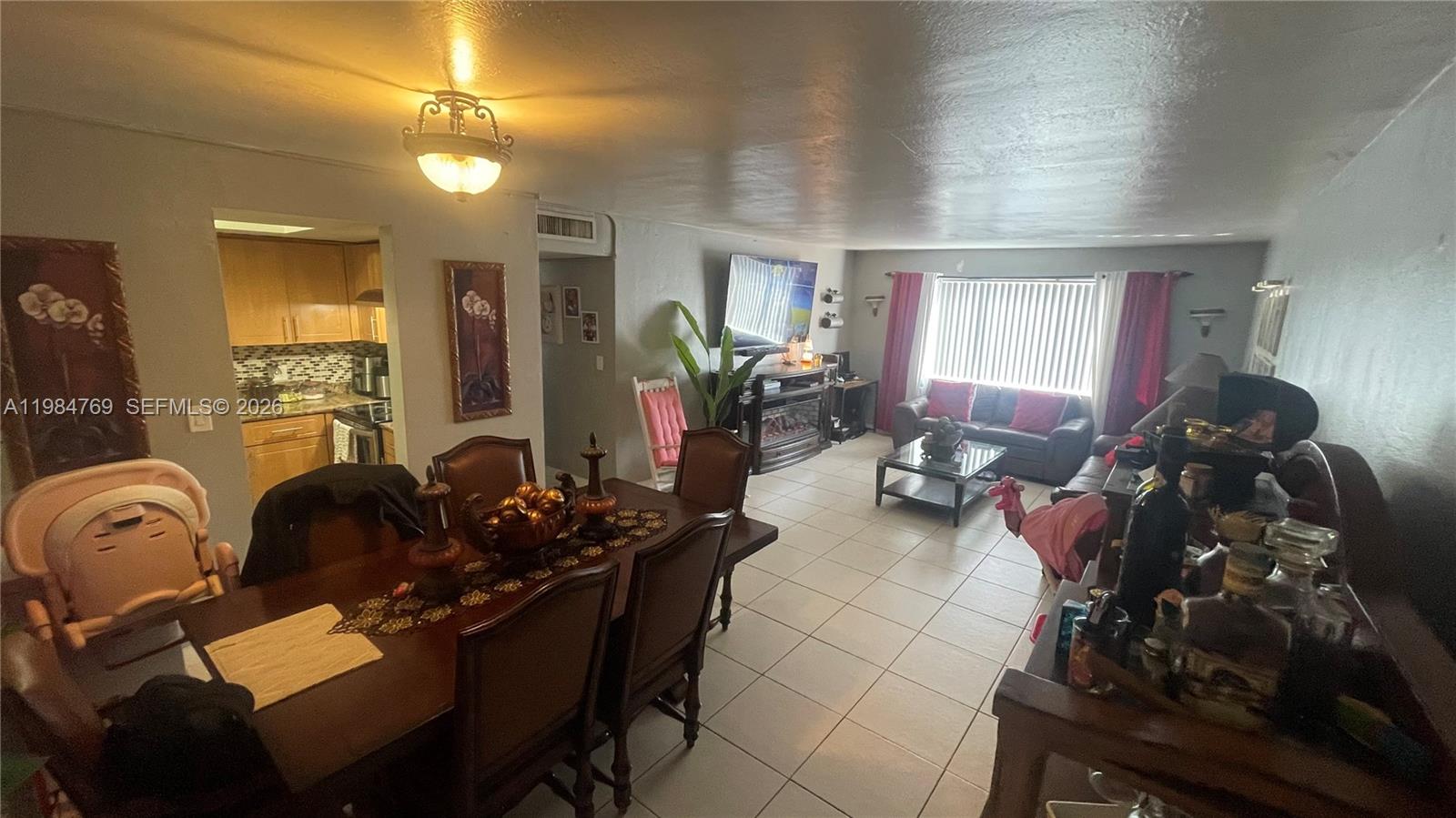 An open-concept living and dining area features tile flooring, a wooden dining set, and kitchen — 13700 NE 6th Ave # 104, North Miami FL 33161, NORTH MIAMI, FL