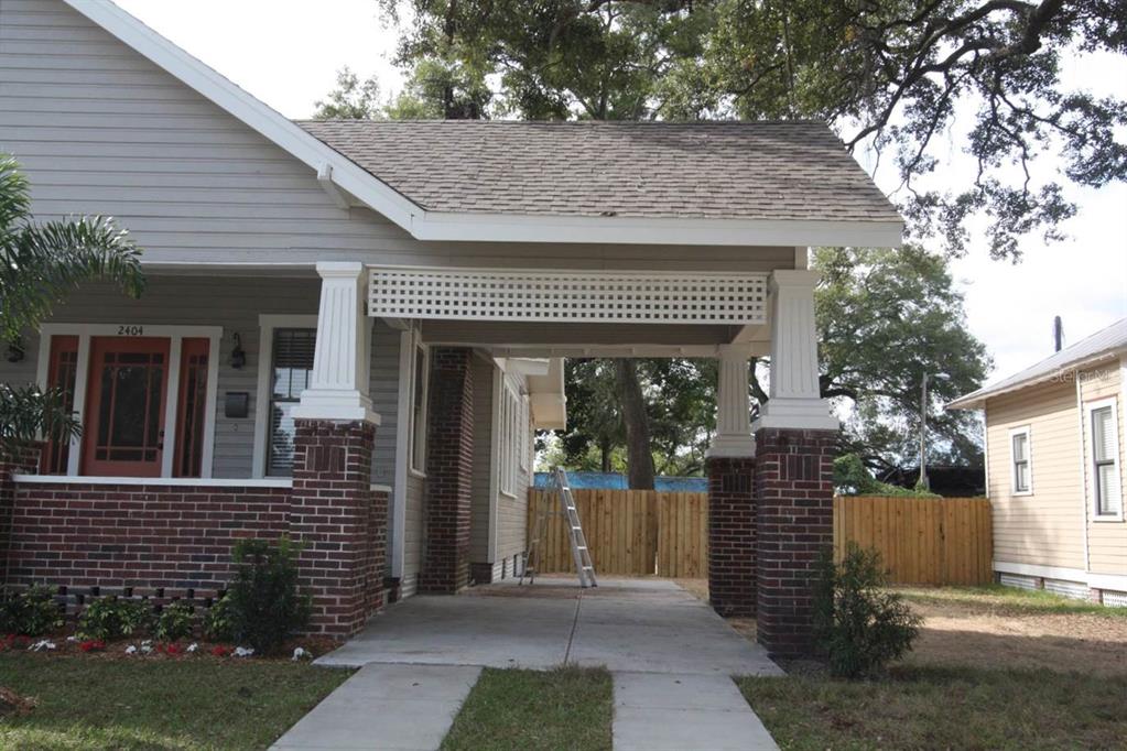 A house exterior features a brick-based carport with white columns and a lattice-covered roof — 2404 N MORGAN STREET, TAMPA, FL