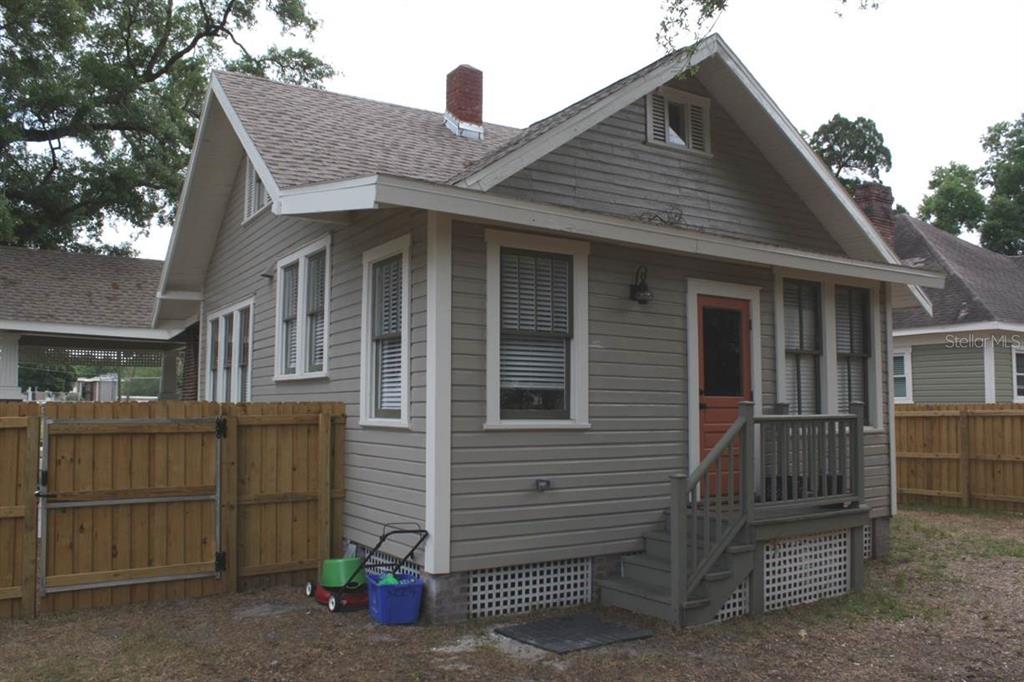 A gray-sided house with a small porch, a wooden fence, and a lawnmower outside — 2404 N MORGAN STREET, TAMPA, FL