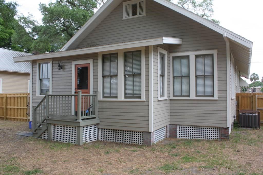 The exterior of a tan, single-story house features a small wooden porch and lattice skirting — 2404 N MORGAN STREET, TAMPA, FL
