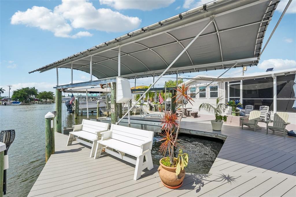 A wooden deck with white benches and a boat lift overlooks a canal — 3050 YORK ROAD, ST JAMES CITY, FL