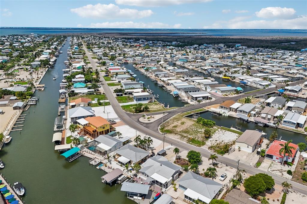 An aerial view shows a residential neighborhood with houses lining canals and a coastal waterway — 3050 YORK ROAD, ST JAMES CITY, FL
