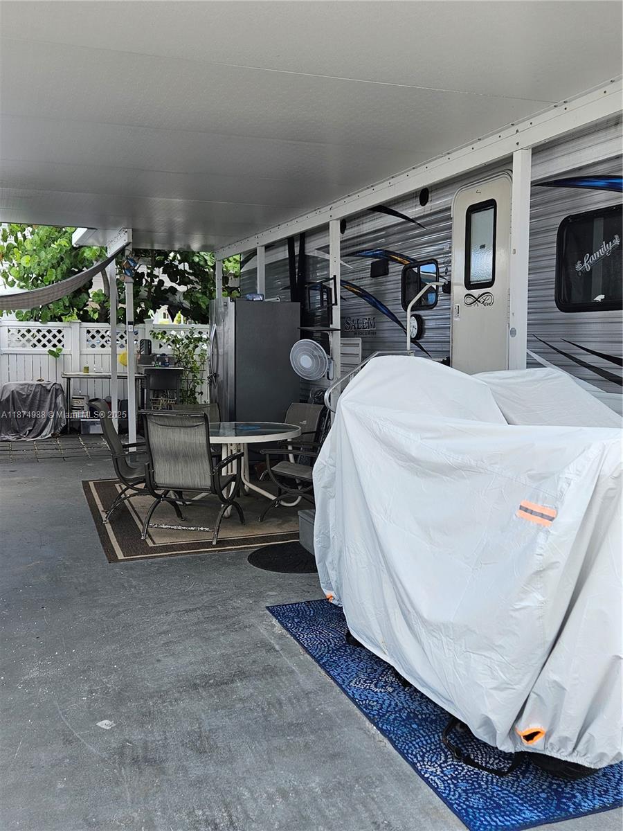 A covered outdoor patio area features a dining set, a refrigerator, and a covered vehicle — 325 Calusa St   #259, Key Largo FL 33037, KEY LARGO, FL