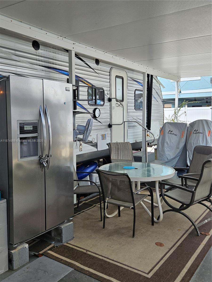 A stainless steel refrigerator sits on a patio next to a travel trailer and table — 325 Calusa St   #259, Key Largo FL 33037, KEY LARGO, FL