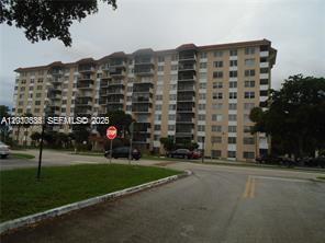A multi-story residential apartment building stands behind a parking lot and a stop sign — 4174 Inverrary Dr # 911, Lauderhill FL 33319, LAUDERHILL, FL