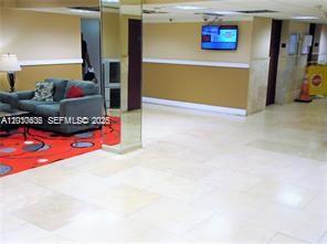 A lobby area features a gray sofa on a patterned rug and tiled flooring — 4174 Inverrary Dr # 911, Lauderhill FL 33319, LAUDERHILL, FL