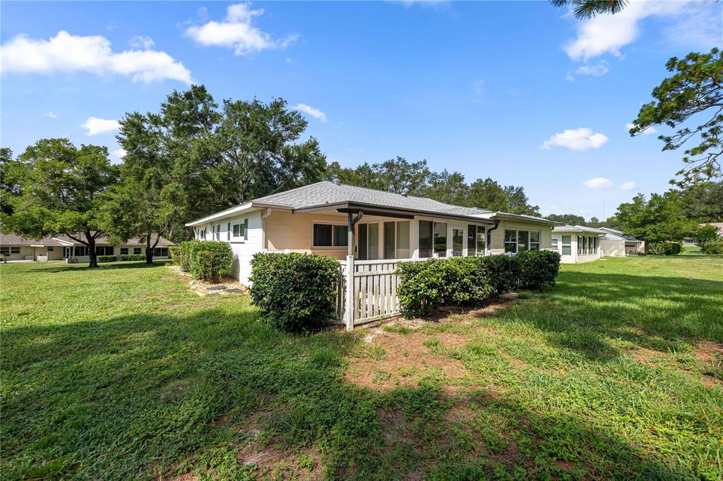 The exterior of a single-story house features a screened-in patio and surrounding green lawn — 9920 SW 89TH COURT ROAD UNIT F, OCALA, FL