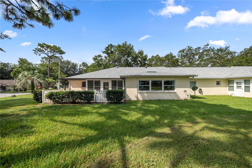 The exterior rear view of a single-story house with a screened porch and grassy yard — 9920 SW 89TH COURT ROAD UNIT F, OCALA, FL