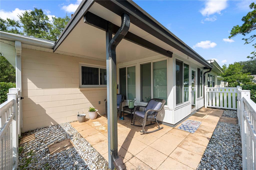 A paved patio area features a covered porch, white railings, and a glass-enclosed sunroom — 9920 SW 89TH COURT ROAD UNIT F, OCALA, FL