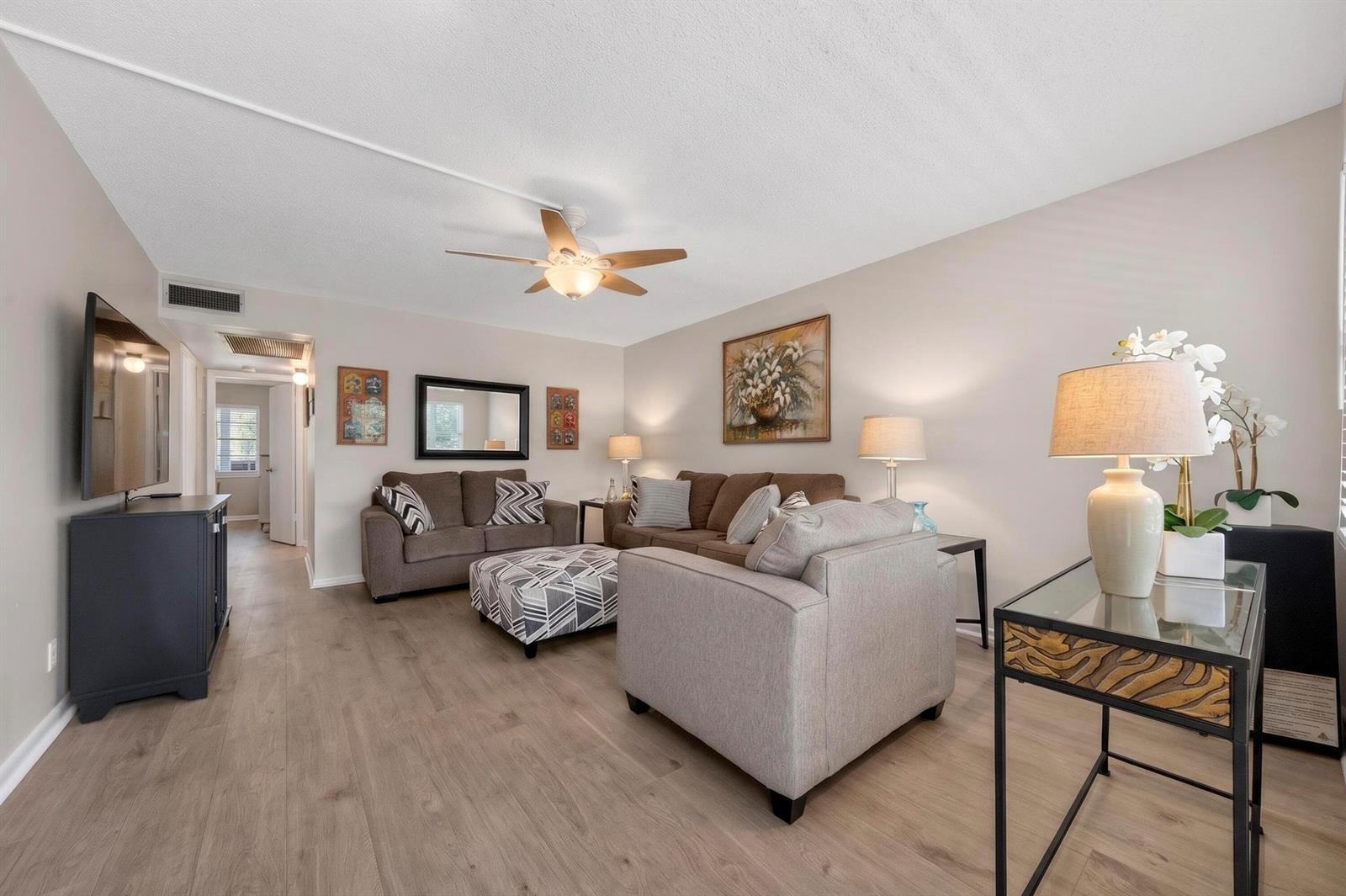 A living room features light wood-look flooring, a ceiling fan, and neutral-colored furniture — 2002 Berkshire A # 2002, Deerfield Beach FL 33442, DEERFIELD BEACH, FL