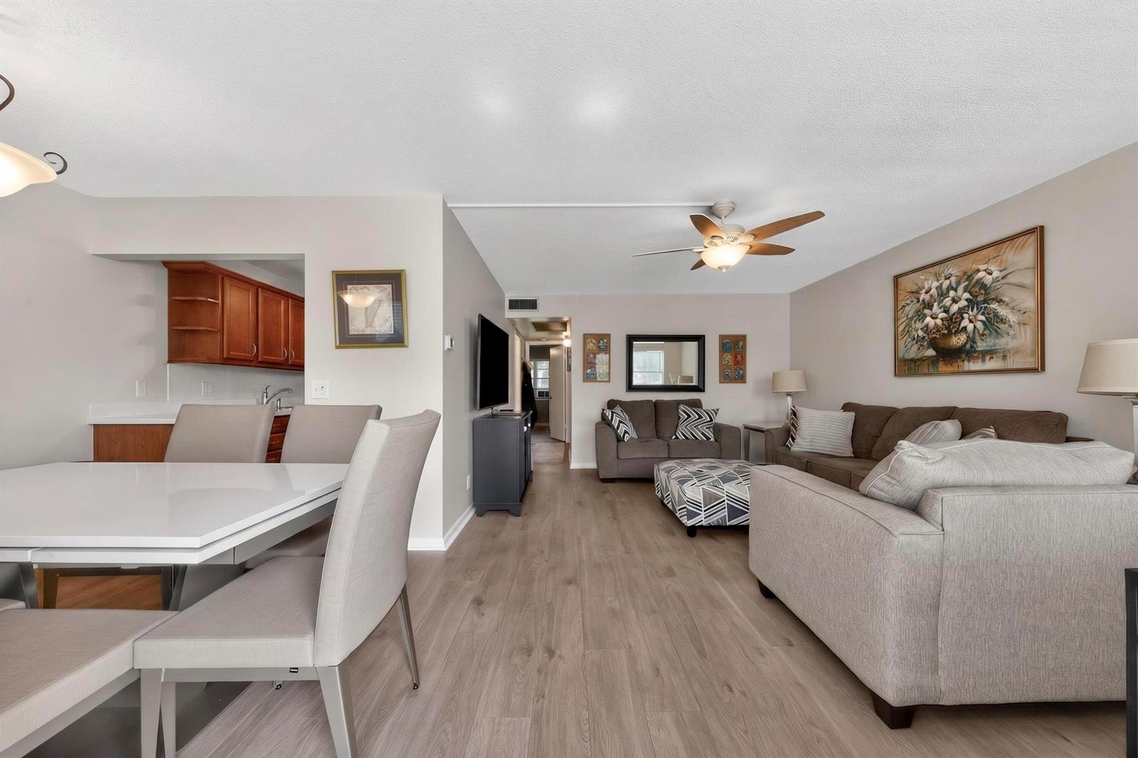 A living room and dining area with light wood flooring, neutral walls, and modern furniture — 2002 Berkshire A # 2002, Deerfield Beach FL 33442, DEERFIELD BEACH, FL